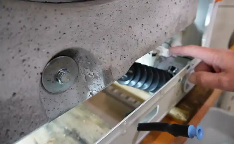 Drain pump access and spring assembly showing mineral buildup area